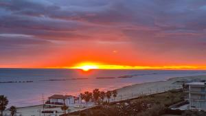 a sunset over a beach with a building and the ocean at GRAND HOTEL OLIVIER PRINCe in Roseto degli Abruzzi