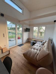 a living room with a large couch and windows at Tinyhaus Ferien in Eggolsheim