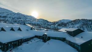 a house covered in snow with the sun in the background at Sirdal Høyfjellshotell in Fidjeland