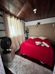 a bedroom with a red bed with slippers on it at Lua de Aquarius Boutique Hostel in Tamoios