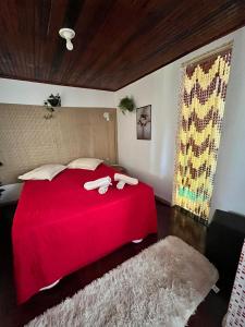 a bedroom with a red bed with two towels on it at Lua de Aquarius Boutique Hostel in Tamoios +29 photos