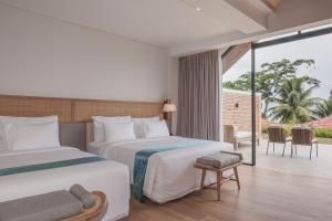 a hotel room with two beds and a balcony at Marianna Resort And Convention Tuktuk - Samosir, Marclan Collection in Tuktuk Siadong