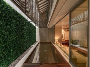 an indoor swimming pool with a green wall at Brown Feather Pererenan in Canggu