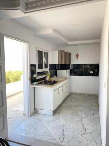 a kitchen with white counters and a large window at Maison a midoun in Midoun