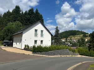 a white house on the side of a road at Traumhaus in der Eifel in Hellenthal