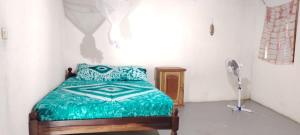 a bedroom with a bed with a green comforter at Campement Outouka in Kafountine