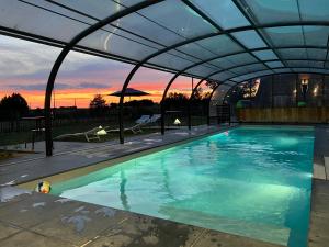 a swimming pool under a retractable roof at sunset at Les Chambres de Ribeaufontaine in Dorengt