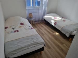 two twin beds in a room with a wooden floor at Le Stein in Steinbach