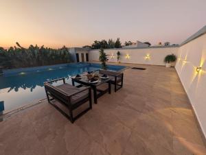 a patio with a table and chairs next to a pool at Prakruthi Retreat Belagavi in Belgaum