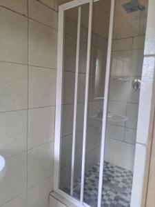 a shower with a glass door in a bathroom at Snooze Guesthouse in Roodepoort +16 photos