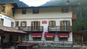 a building with red awnings and tables in front of it at Affittacamere Valle Dorizzo di Scavoni Paolo in Val Dorizzo
