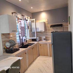a kitchen with wooden cabinets and a black refrigerator at Fayalobi in Saint-Laurent du Maroni