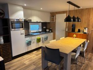 a kitchen with a wooden table and a kitchen with white appliances at Bospark Wolfsven - 1511 in Mierlo