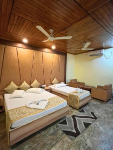 a bedroom with two beds and a ceiling fan at Gorumara Jungle Resort in Chālsa