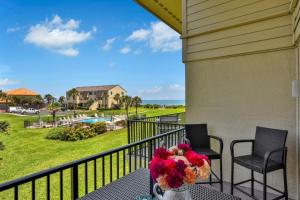a balcony with two chairs and a table with flowers at Summerhouse 147 condo in St. Augustine