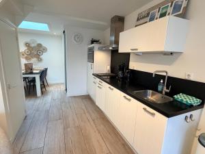 a kitchen with white cabinets and a sink and a table at SummerTime Bergen aan Zee in Bergen aan Zee +46 photos
