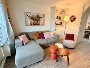 a living room with a couch and a bull painting on the wall at SummerTime Bergen aan Zee in Bergen aan Zee