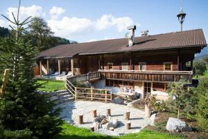 ein großes Holzhaus mit einer Terrasse davor in der Unterkunft Bergchalet Rauchenhof in Reith im Alpbachtal