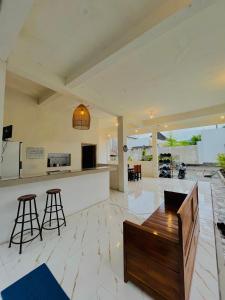 an open kitchen and living room with a bar and stools at NeNa Eat & Sleep Kuta in Kuta Lombok