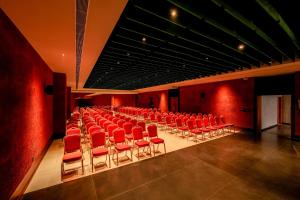 an empty auditorium with red chairs and red walls at Nestlay Suites by TC One in Kozhikode +116 photos