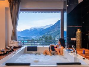 a woman sitting in a bath tub with a view at Moustache Manali in Manāli