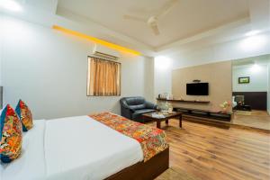 a bedroom with a bed and a chair and a television at HHW Hotel- Agra in Agra