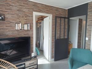 a living room with a television and a brick wall at les vagues a Bénodet in Bénodet