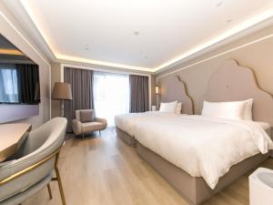 a hotel room with a large bed and a chair at Mercure Turpan Downtown in Turfan