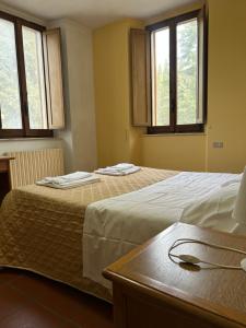 two beds in a room with windows and a table at Casa per Ferie Ulivo d'Assisi in Assisi