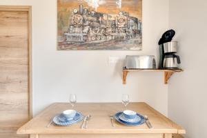 a wooden table with two plates and glasses on it at L'écrin de Sérénité - CNPE Bugey - Meximieux in Meximieux