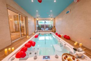 a large pool with a hot tub in a room at Suites Romantiques avec Jacuzzi - Marne-La-Vallée - Le Jardin De Vos Secrets in Mouroux