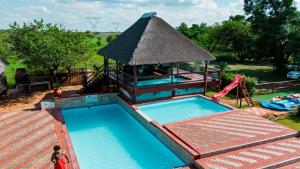 a swimming pool with a gazebo and a playground at Falcon Lodge PK in Bela-Bela