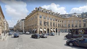 a city street with cars parked in front of a large building at Le Stendhal - Vendôme in Paris