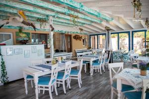 a restaurant with white tables and chairs and windows at Casa din Delta in Murighiol