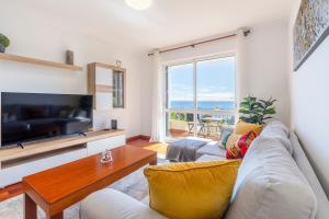 a living room with a couch and a large window at BoLina Ocean View in Caniço