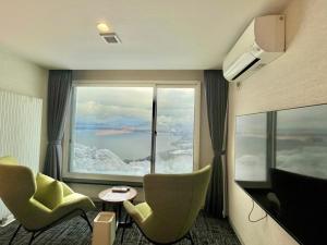 a room with a large window with chairs and a table at HOTEL COCOA RESORT in Lake Toya
