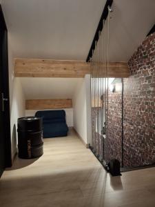 a room with a brick wall and a blue couch at La Source in La Croix-Saint-Leufroy