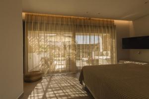 a bedroom with a bed and a large window at Acacia - Explore your senses in Preveza