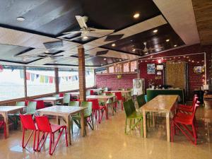 a restaurant with tables and chairs in a room at Hotel Sumit in Kausani