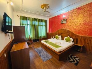 a bedroom with a bed and a flat screen tv at Hotel Sumit in Kausani