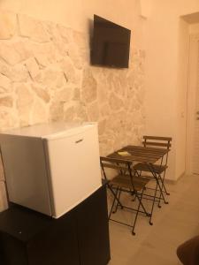 a refrigerator and a table and a tv on a wall at B&B Santa Chiara Home in Caserta