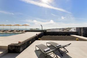 a patio with two chairs and a swimming pool at Ocean View Lanzarote by Beyond in Tías