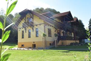 a large yellow house with trees in front of it at Penzión na Ráztočnom in Klenovec +7 photos
