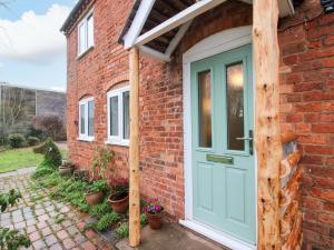 a brick house with a green door at 1 Dingle Cottage in Worcester