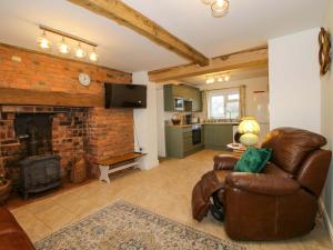 a living room with a leather chair and a fireplace at 1 Dingle Cottage in Worcester