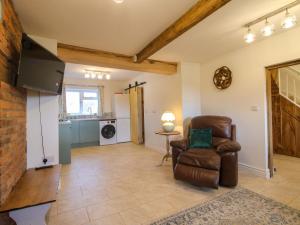 a living room with a chair and a television at 1 Dingle Cottage in Worcester