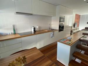 a kitchen with white cabinets and a wooden table at Casa dos Coelhos in Moledo