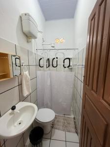 a white bathroom with a toilet and a sink at Pousada Maia in Itaúnas