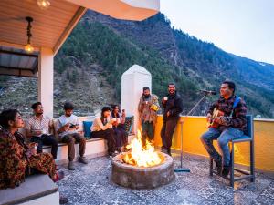 a group of people sitting around a fire on a boat at Moustache Manali in Manāli