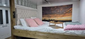 a large bed with pink and blue pillows on it at The Orchard's Nook Treehouse in Cottenham